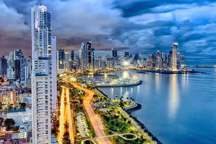 Panoramic twilight view of Panama City skyline and illuminated coastal highway for Yala Ride car rental services.